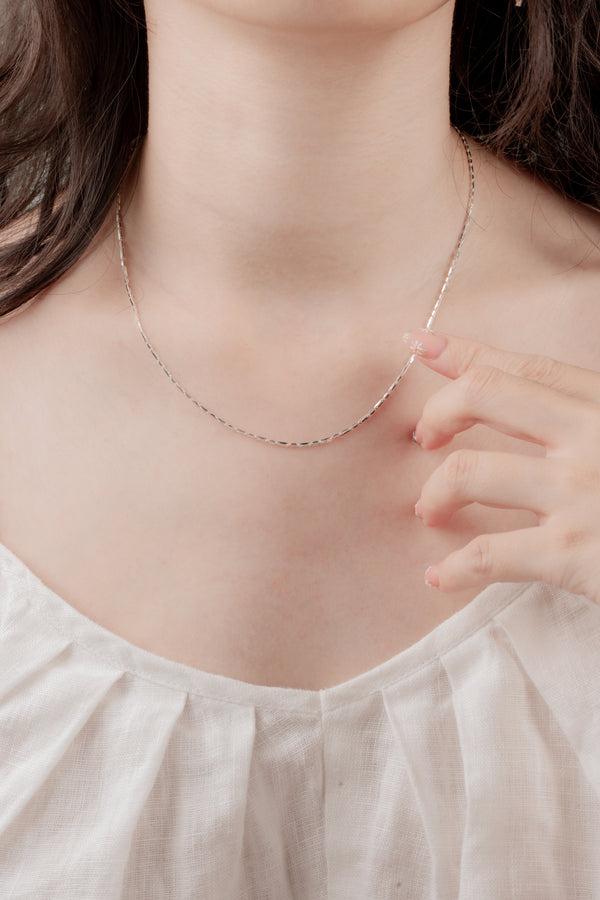 Close-up of the Apple Gleam Necklace, featuring intricate silver craftsmanship and a luminous 20-inch adjustable chain
