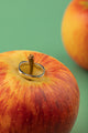 Oval Edge Ring resting against a red apple on a white stone block – modern minimalist jewelry.