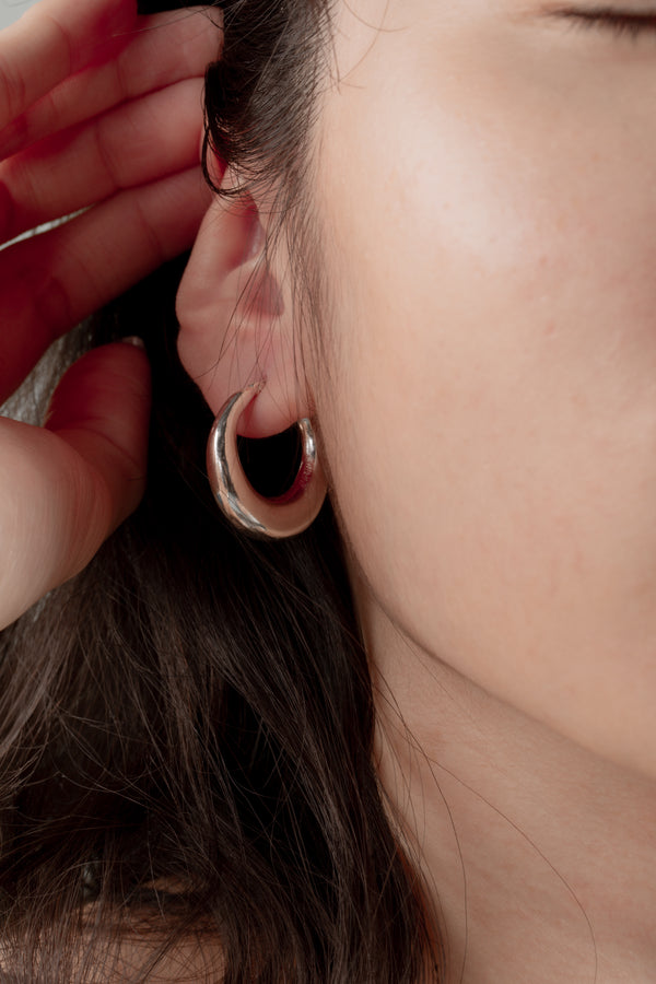 Close-up of the Timeless Glow Earrings, featuring a polished 30mm crescent design with a radiant silver finish