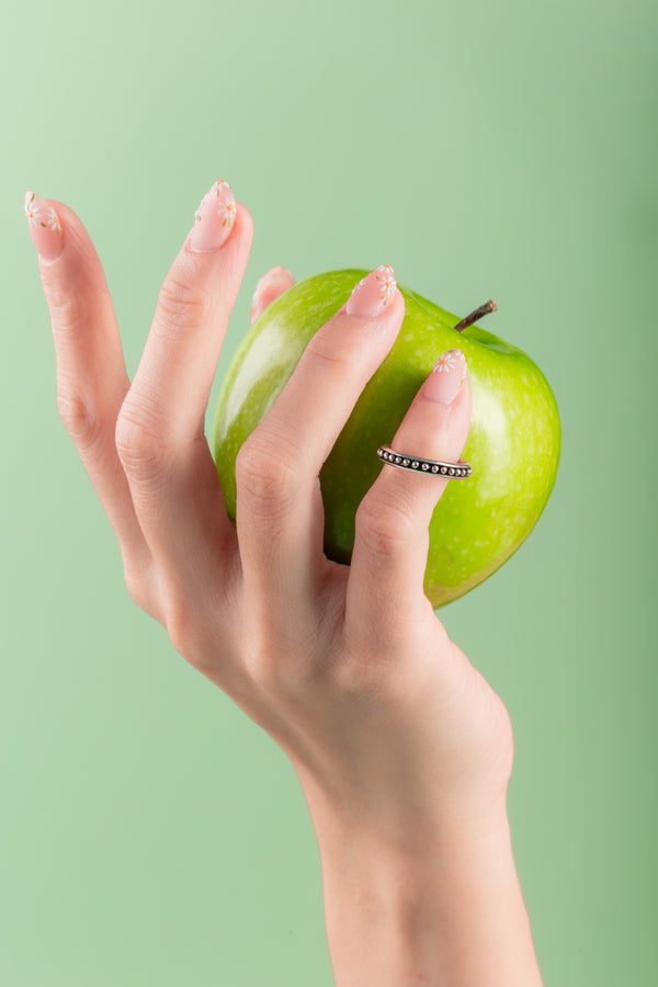 Close-up of minimalist silver ring adorned with vibrant citrus-colored beads