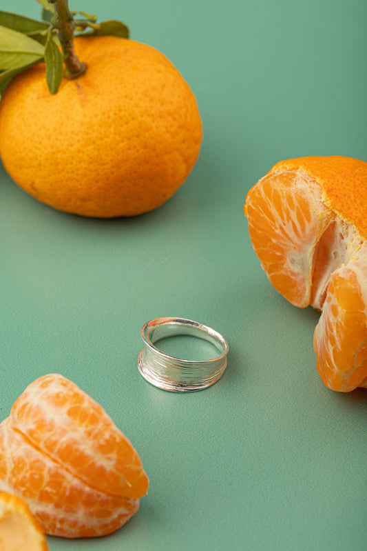 Jewelry flatlay of Horizon Curve Ring with soft green backdrop.