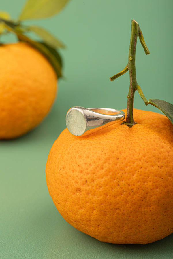 Sculptural silver ring resting on citrus – part of Argenté Jewelry’s Minimal Collection