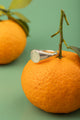 Sculptural silver ring resting on citrus – part of Argenté Jewelry’s Minimal Collection