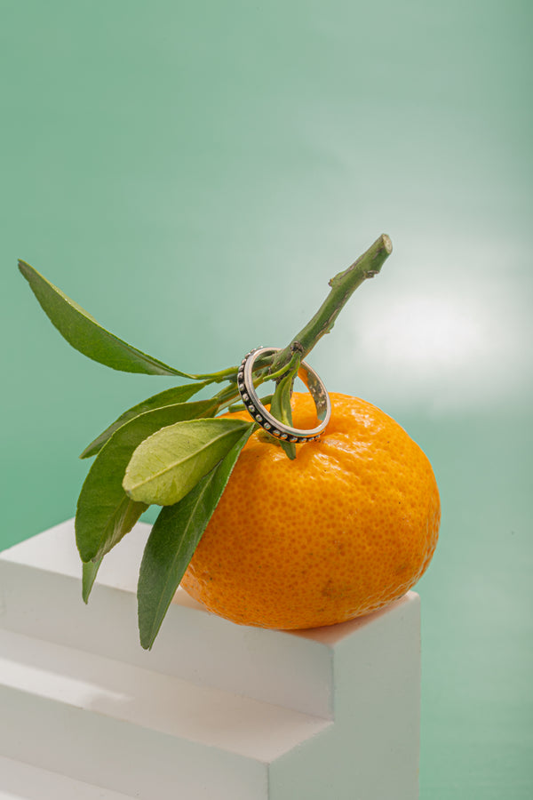 Citrus-inspired beaded ring styled alongside other minimalist jewelry pieces.